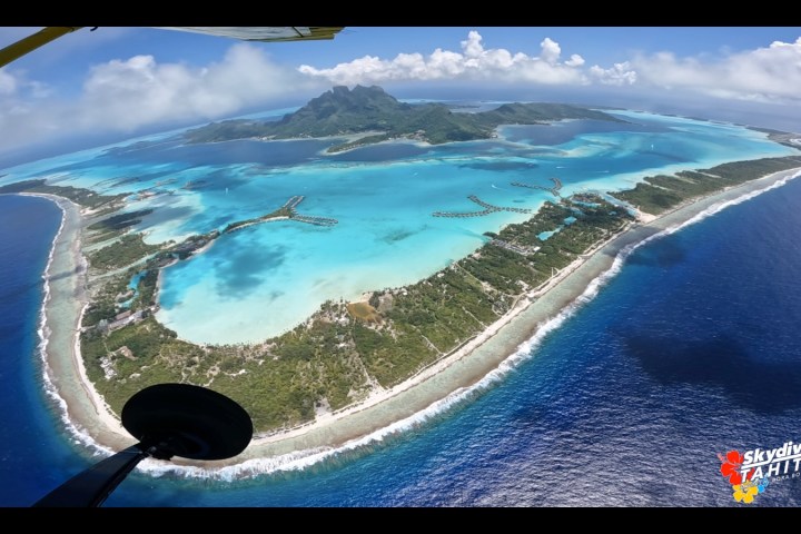 Aerial view of tropical island with turquoise waters and mountainous landscape.